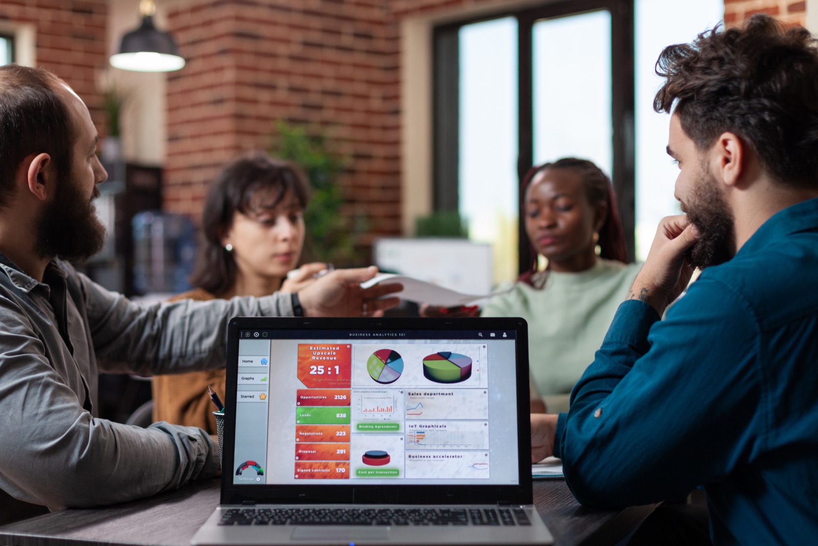 Equipe analisando gráficos de marketing digital em um laptop